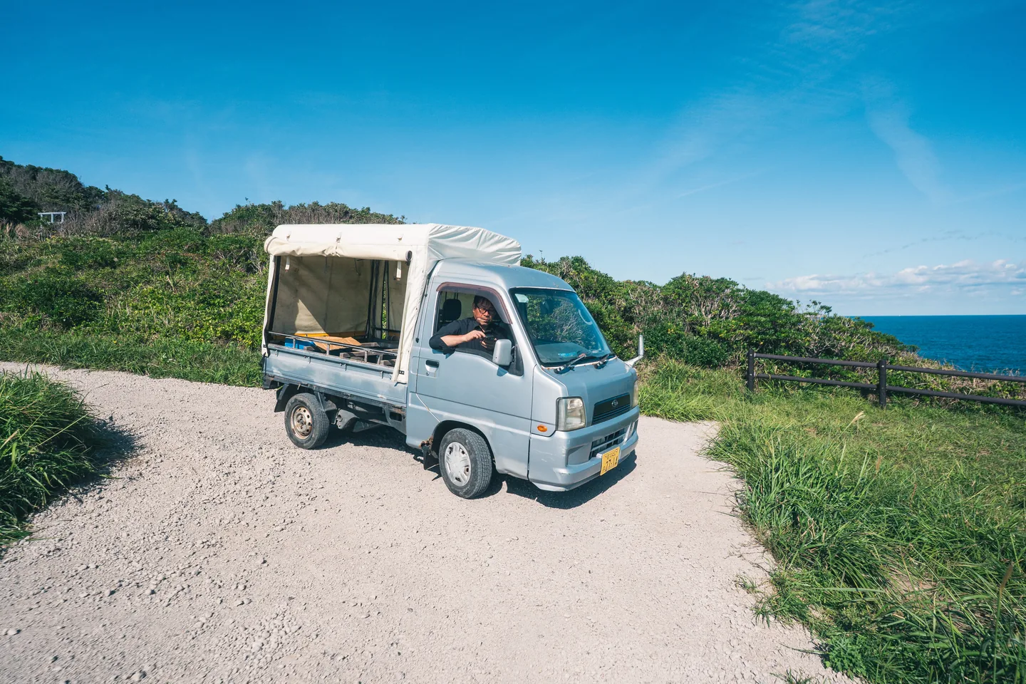 海の見える道に停まる軽トラック
